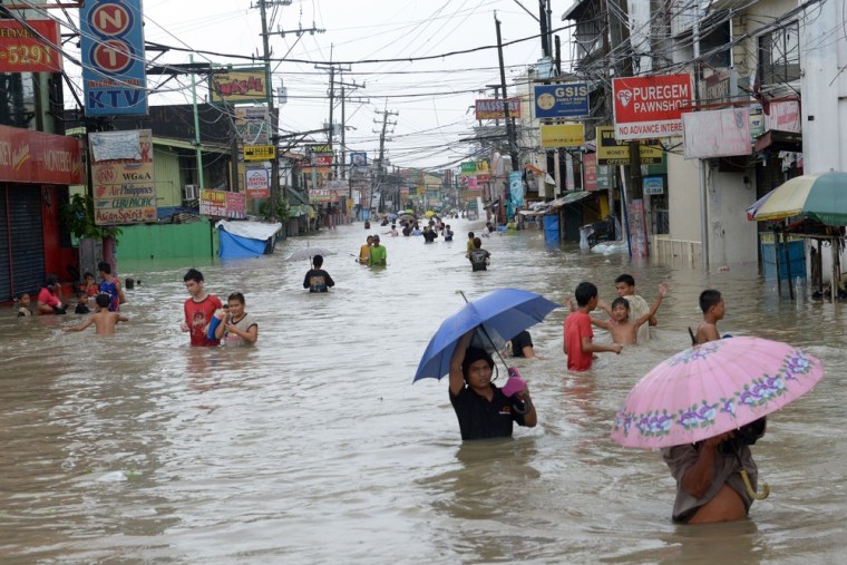 Residents wade through flood waters in the farming town of Novaleta, some 26 kilometres outside Manila. Torrential rain paralysed large parts of the Philippine capital as neck-deep water swept through homes, while floods in northern farming areas claimed at least one life.