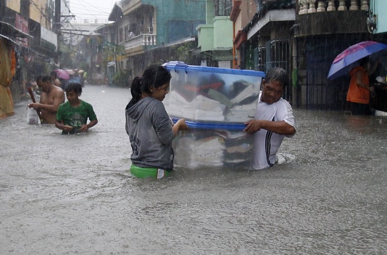 Residents carry their belongings as they wade through flood waters. Heavy rains continue to batter the Philippine capital and nearby provinces, causing government offices, schools and some businesses to suspend work, and sending residents to flee their homes.