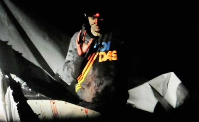 19-year-old Boston Marathon bombing suspect Dzhokhar Tsarnaev raises his hand from a boat at the time of his capture by law enforcement authorities in Watertown, Mass.