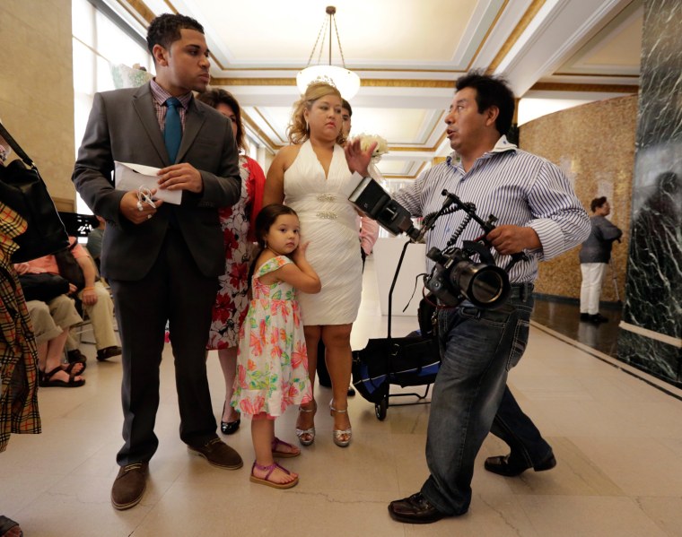 Wedding photographer Braulio Cuenca, right, talks with groom Jorge Mejia and bride Irma Aguilar, from the Bronx, before their ceremony at New York's Office of the City Clerk on Aug. 7, 2013.