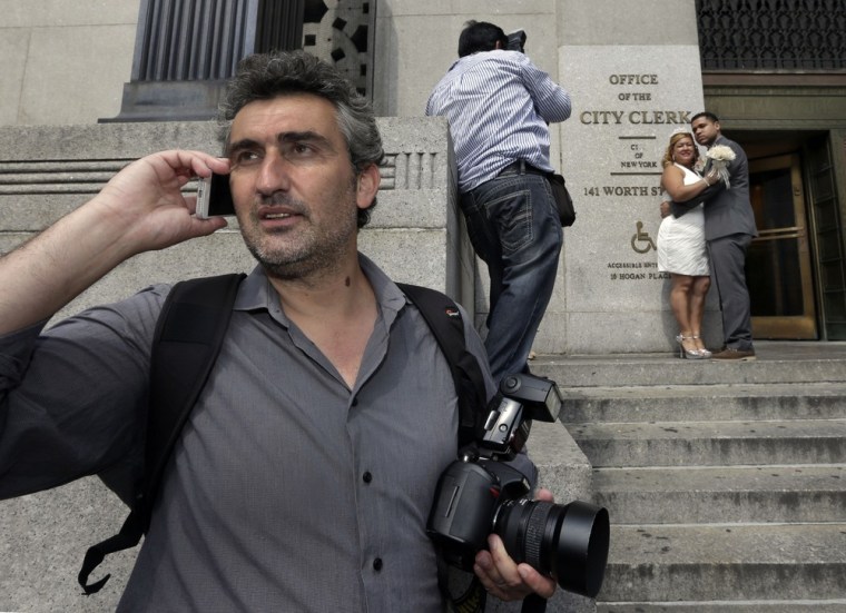 Goran Veljic, left, waits to be hired as Braulio Cuenca shoots pictures of Jorge Mejia and Irma Aguilar outside City Hall. Between them, the two wedding photographers have served as witnesses for thousands of couples.