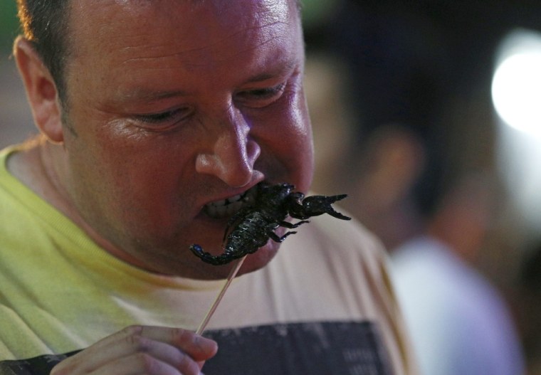 A foreign tourist eats a fried scorpion at Khao Sarn road, a tourist area in Bangkok, Thailand, on July 20.