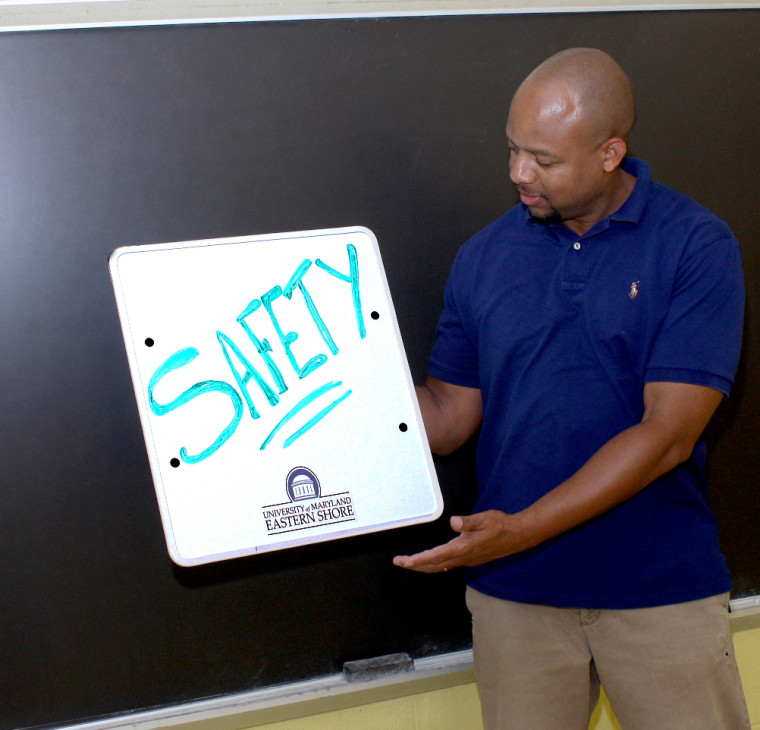 UMES' Marcellus Connor demonstrates how a new type of hand-held writing tablet, similar to stationary whiteboards used in classrooms, can double as bulletproof protection for educators.