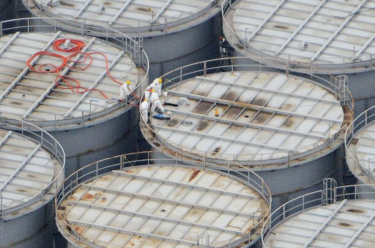 Workers stand on storage tanks at the Fukushima Daiichi nuclear plant at Okuma, northern Japan, on Aug. 20, 2013.