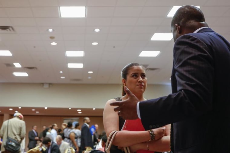 A woman stands with her paperwork as she speaks with a recruiter while attending a job fair in New York, June 11, 2013.