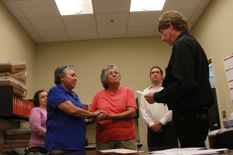 Catherine Martinez and Linda Montoya hold hands as Dona Ana County employee and reverend Jess C. Williams marries them at the County Clerk's Office in Las Cruces, New Mexico, on Wednesday.