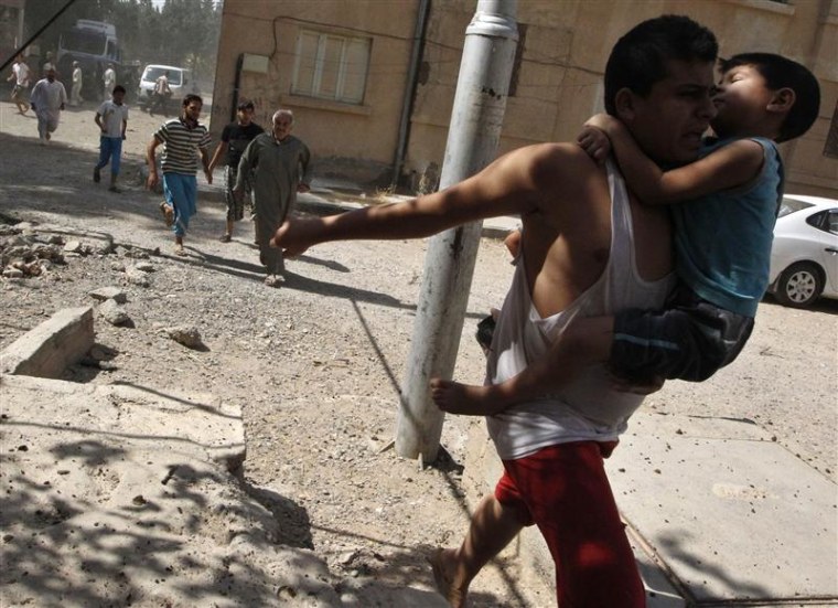 A man carries a boy as he runs with other civilians to take cover after what activists said was a missile strike by Syrian Air Force fighter jets loyal to President Bashar al-Assad, in Raqqa province, eastern Syria August 21, 2013.