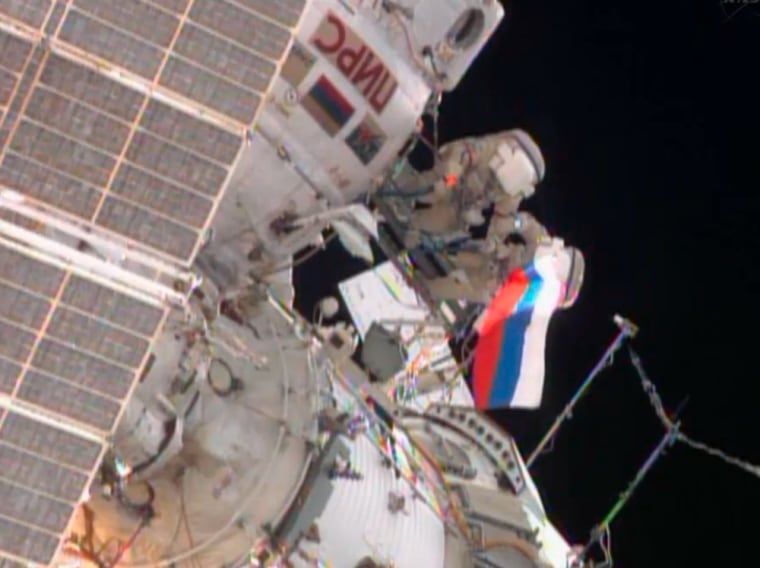 In this image from NASA video, cosmonauts Aleksandr Misurkin and Fyodor Yurchikhin wave a Russian flag during their spacewalk outside the Internationa...