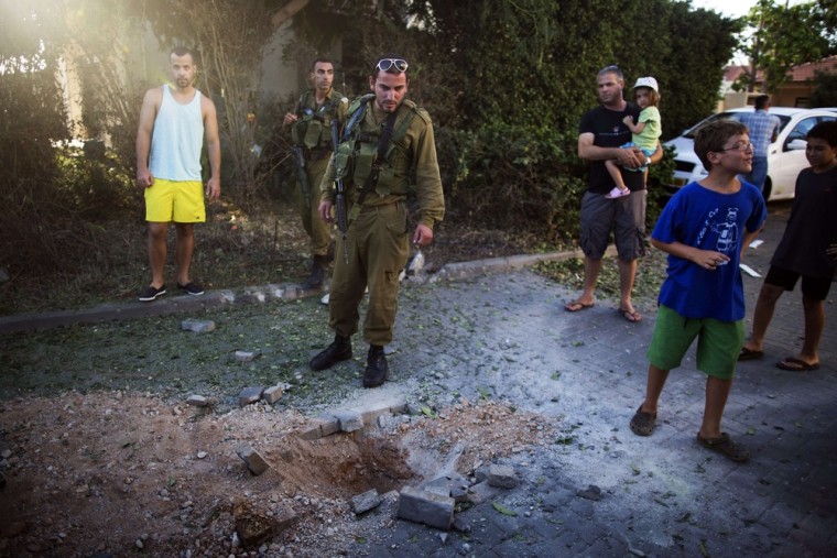 An Israeli soldier inspects the damage caused by a rocket fired from Lebanon into the Gesher Haziv kibbutz in northern Israel Thursday.