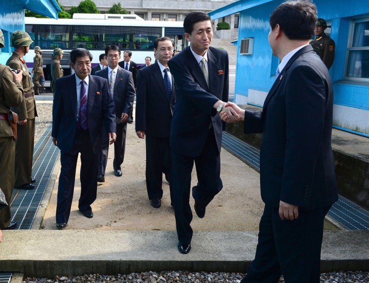 The head of North Korea's working-level delegation to family reunions crosses the military demarcation line for a meeting as North Korean soldiers stand guard at border village of Panmunjom on Friday. It has been three years since the last official reunions of Korean families separated during the 1950-1953 Korean War.