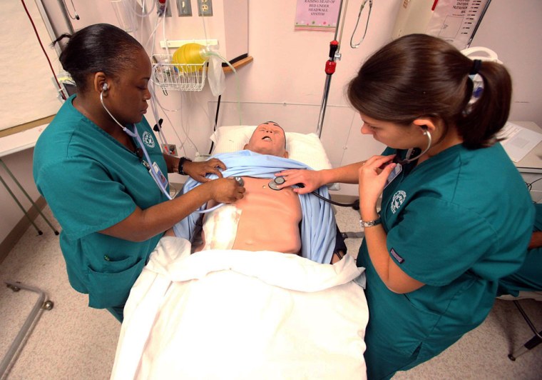 Nursing students Charlyndra Lucious, left, and Tiffany Pendley check the symptoms on a nursing dummy during a senior level associate degree nursing cl...