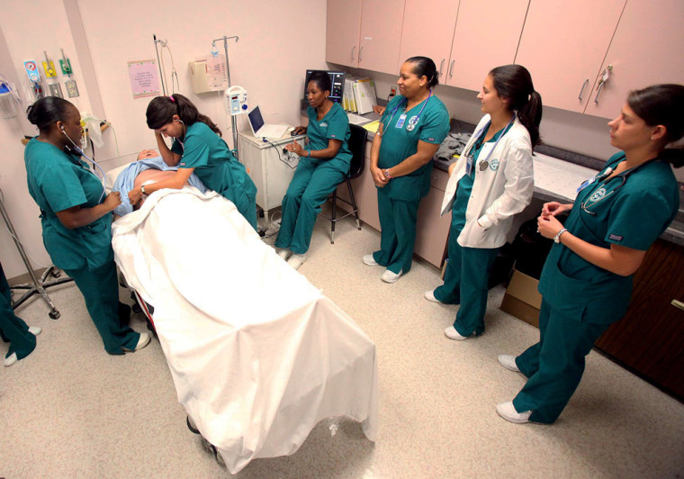 Nursing students check the symptoms on a nursing dummy during a senior level associate degree nursing class at Shelton State Community College in Tusc...