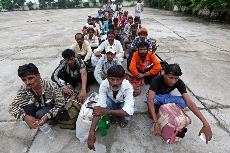 A group of Indian fishermen sits on the ground after their release from a prison as they show their temporary travel documents while crossing into India.