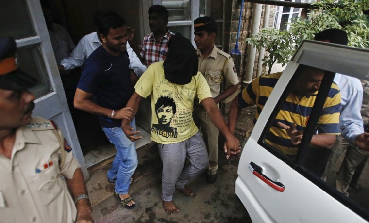 Police officers escort a man (face covered), who was arrested in connection with the gang-rape of a photo journalist, at a court in Mumbai on August 25, 2013.