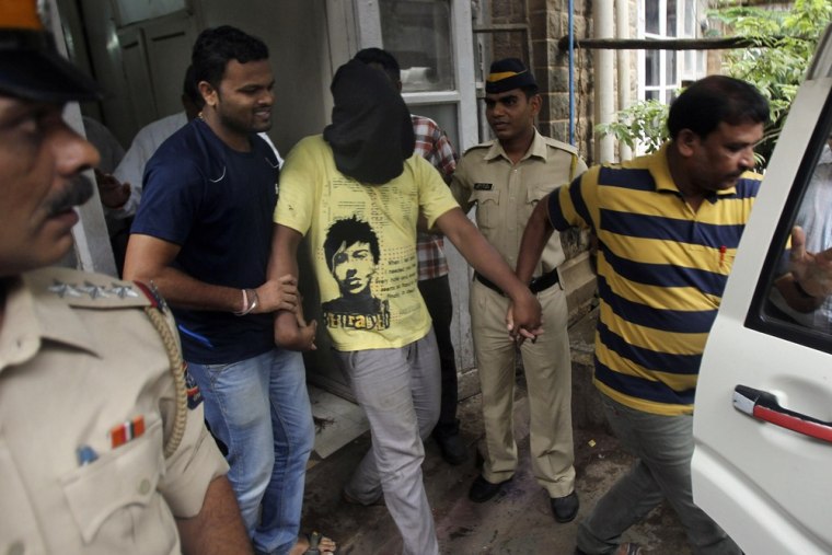 Police officials escort an accused, with the head covered with black cloth, in the gang rape of a photojournalist after producing him before a court in Mumbai, India, Sunday.
