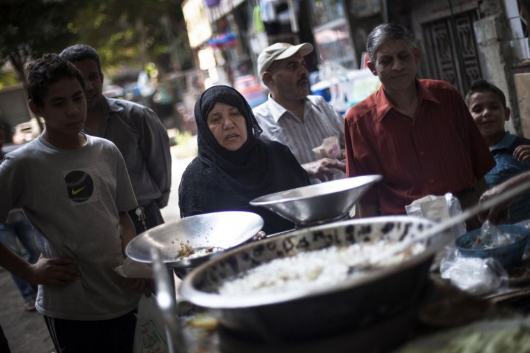 An Egyptian woman waits for her breakfast on a street fast food restaurant in Suleiman Gohar market in Dokki district in Cairo, Egypt, Monday, Aug. 26, 2013. An evening curfew in Egypt to prevent further violence has affected businesses like this restaurant.