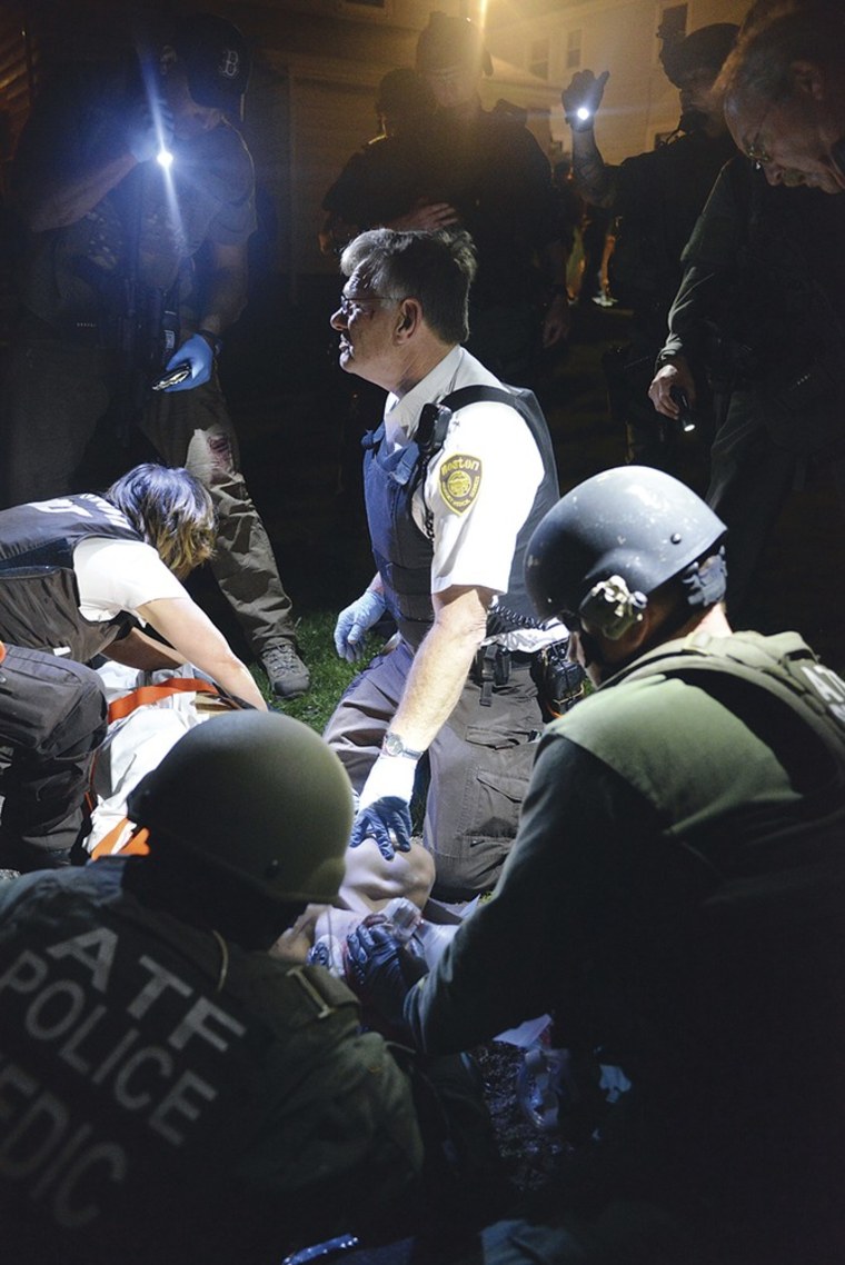 Tactical emergency medical technicians tend to Marathon bombing suspect Dzhokhar Tsarnaev, partially obscured center, at the time of his capture by law enforcement authorities in Watertown, Mass., on April 19, 2013.