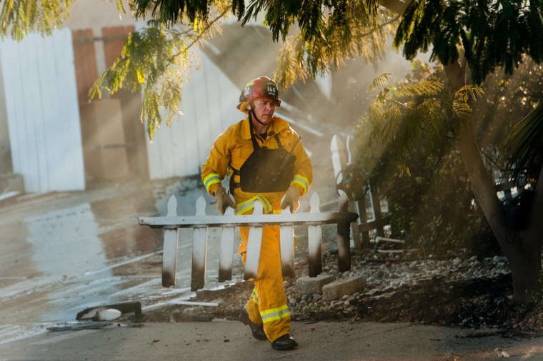 Fairfield firefighter Warren Ducioame moves a burnt picket fence in front of a destroyed home on Marigold Drive in Fairfield, Calif., on Aug. 27, 2013.