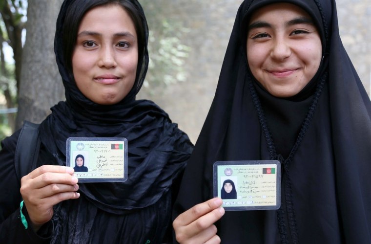 Women show their voter registration cards for Afghan presidential elections scheduled for April 2014, in Kabul, Afghanistan, July 18, 2013.