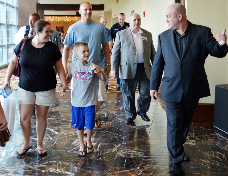 Michigan City Mayor Ron Meer, far right, and Jack Elia, Blue Chip Casino, second right, welcome 6-year-old Nathan Woessner, center, and his parents, Faith, left, and Greg, behind Nathan, of Sterling, Ill., to the Blue Chip Casino in Michigan City, Ind. Tuesday afternoon, Aug. 27, 2013. Michigan City is hosting a pair of events Wednesday to recognize those involved in rescuing Nathan, who was trapped beneath 11 feet of sand for more than three hours at Mount Baldy on July 12. (AP Photo/The News Dispatch, Julie McClure)