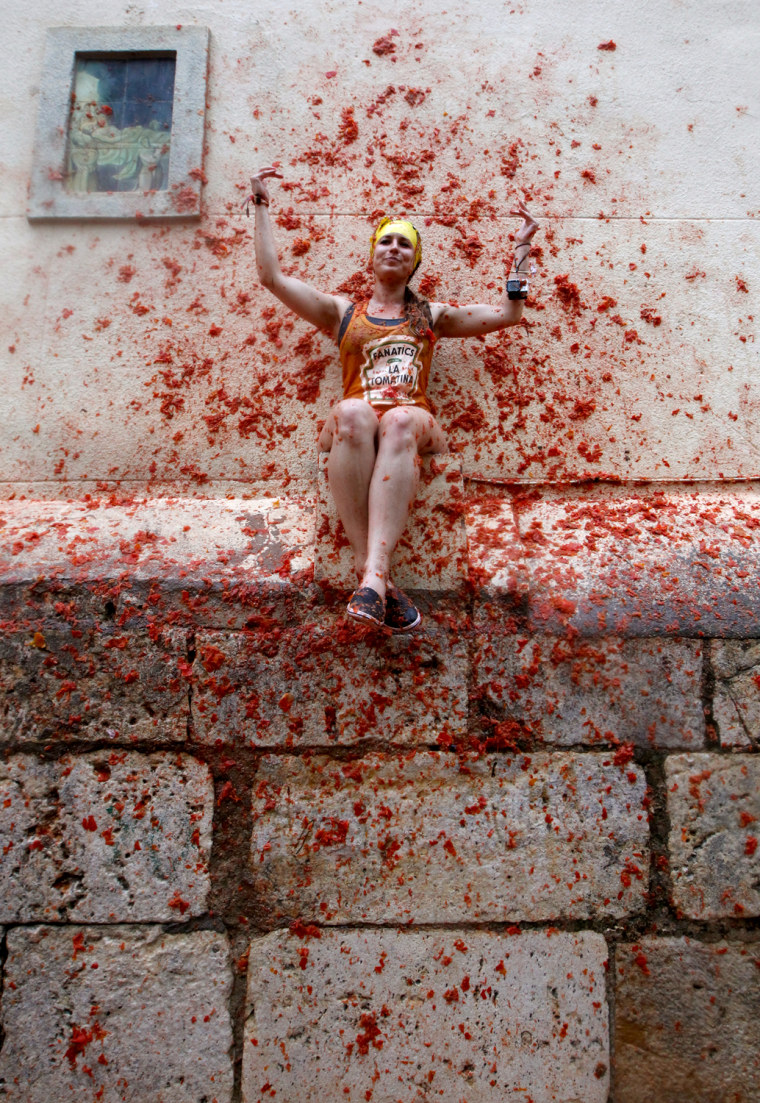 A woman sits on a wall covered by tomato pulp during the annual tomato fiesta in the village of Bunol, outside Valencia, Spain, Aug. 28, 2013.