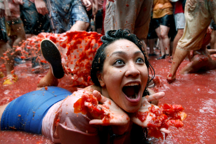 A woman lays on a puddle of tomato juice during the annual