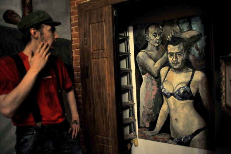 A museum-goer looks at a painting by Russian artist Konstantin Altunin representing Russia's President Vladimir Putin and Prime Minister Dmitry Medvedev in women's lingerie on Aug. 21, 2013.