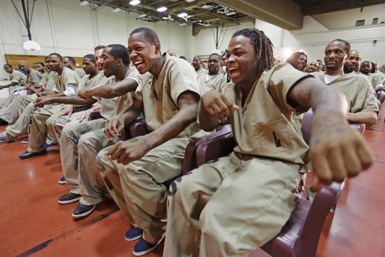 Inmates, from left, Eric McNeil, Kevin Fields, and Julian Campbell, dance in their seats while watching the performance.