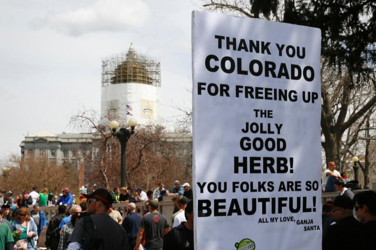 A man holds a sign referring to Colorado legalizing marijuana with the state capitol dome in the background in downtown Denver in this April 20, 2013 file photo. In November, Colorado and Washington state passed laws allowing marijuana for adults for recreational use under certain guidelines.