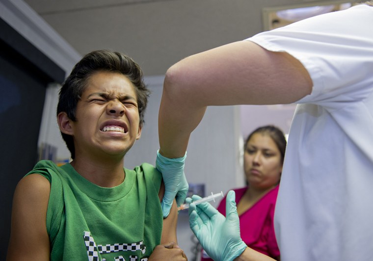 Public school student Julio Valenzuela, 11, grimaces as he gets a vaccination at a free immunization clinic for students before the start of the schoo...