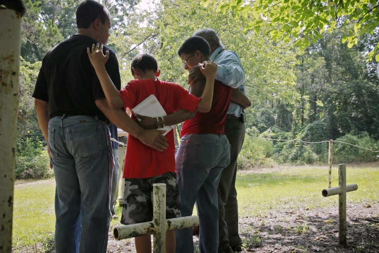 From left, Steven Barnes, 61, of Smyrna, Ga., his son Jason Due-Barnes, 9, wife Tananarive Due, 47, and her father John Due, 78, of Atlanta, embrace during a memorial ceremony Saturday at the cemetery of the former Arthur G. Dozier School for Boys in Marianna, Fla. John Due's wife's uncle died at the school in 1937 after he was stabbed by another student.