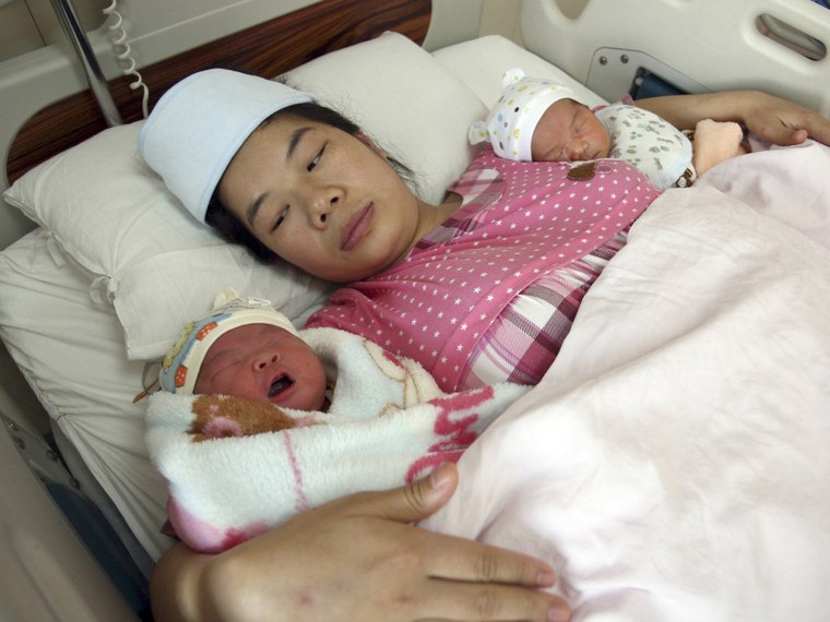 A woman holds her newborn twins in a hospital in Changsha in south China's Hunan province on Nov. 16, 2013. The government recently announced the first easing of the country's strict one-child policy in three decades.