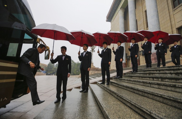 Attendants hold umbrellas to protect delegates from rain as they arrive for the opening ceremony of 21st Century Council Conference at Beijing's Great Hall of the People in November.