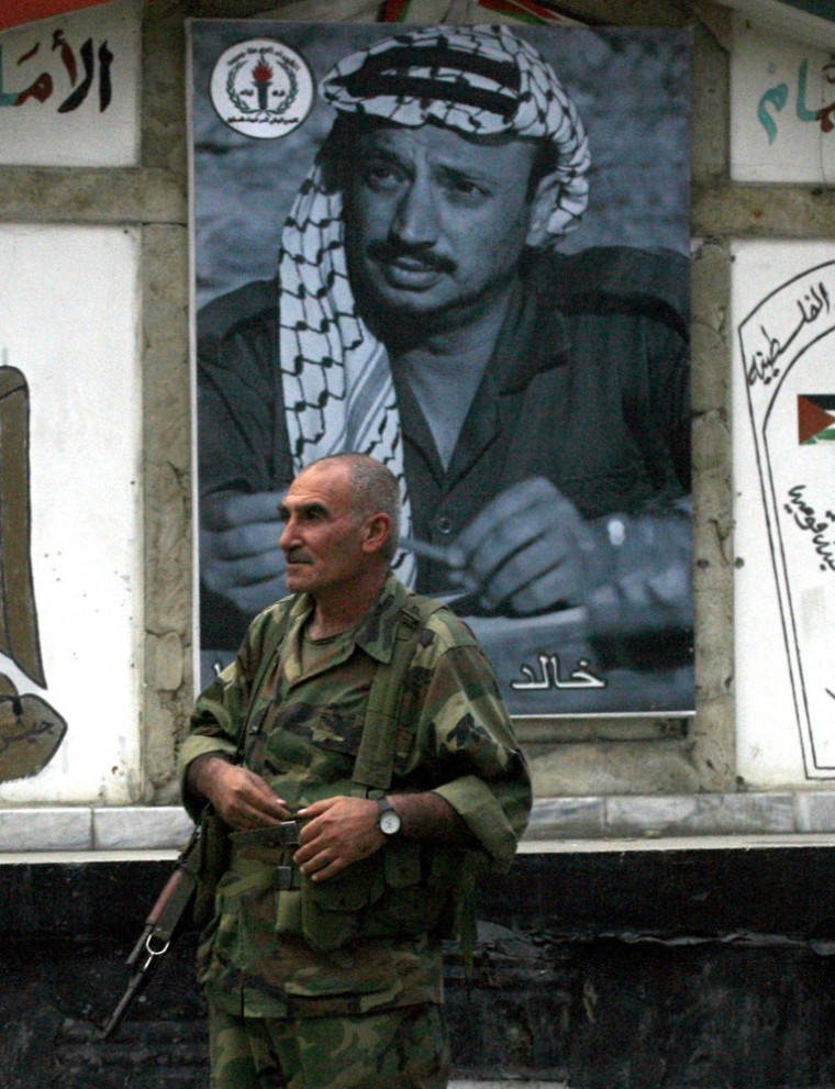 A member of Fatah movement's security forces stands guard next to a poster of late Palestinian leader Yasser Arafat on December 3, 2013 in the Palestinian refugee camp of Ain el-Helweh, in southern Lebanon. French experts have ruled out a theory that Yasser Arafat was killed by poisoning, a source close to the investigation into the Palestinian leader's 2004 death told AFP.