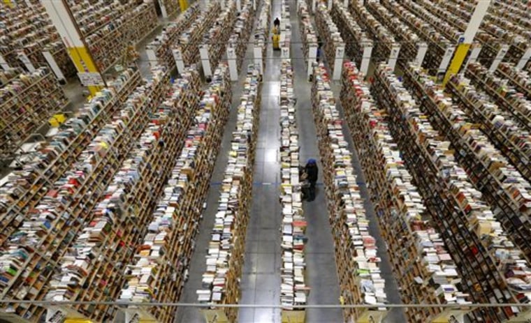 An Amazon.com employee stocks products along one of the many miles of aisles at an Amazon.com Fulfillment Center on