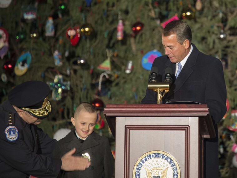 U.S. Speaker of the House John Boehner watches as 6-year-old Giovanni Gaynor is made an honorary Capitol police officer by U.S. Capitol Police Chief Kim Dine, left, before lighting the Capitol Christmas Tree on Tuesday.