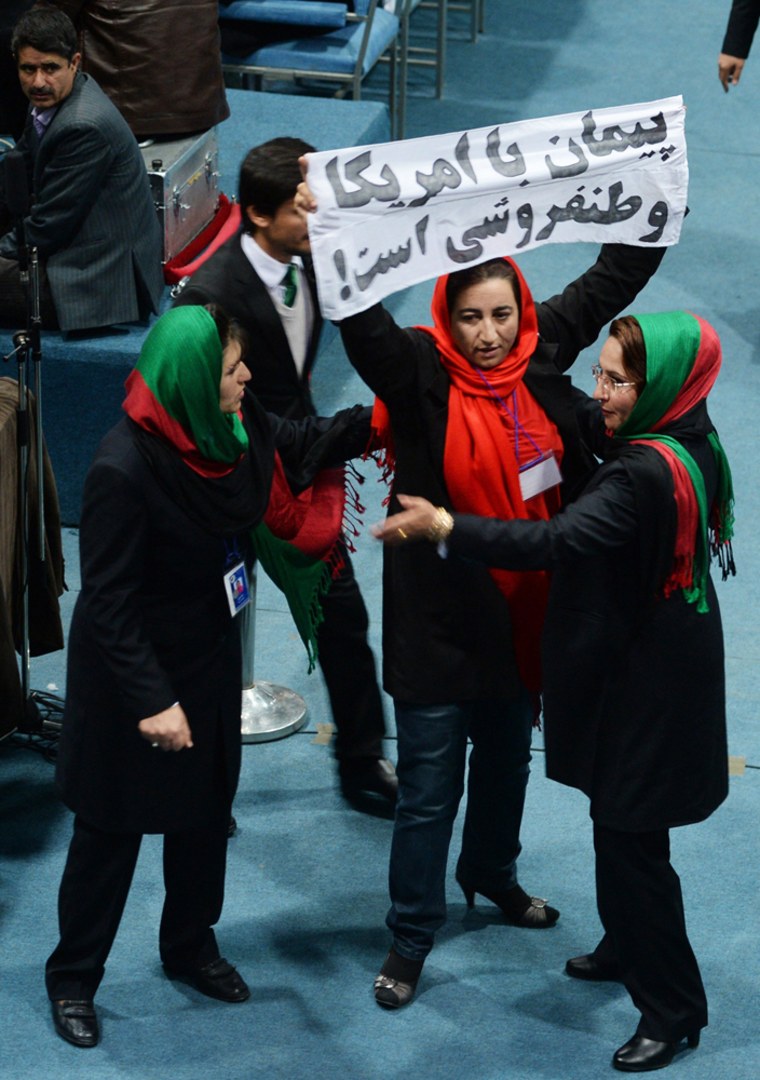 An Afghan protester is approached by security as she holds up a banner reading