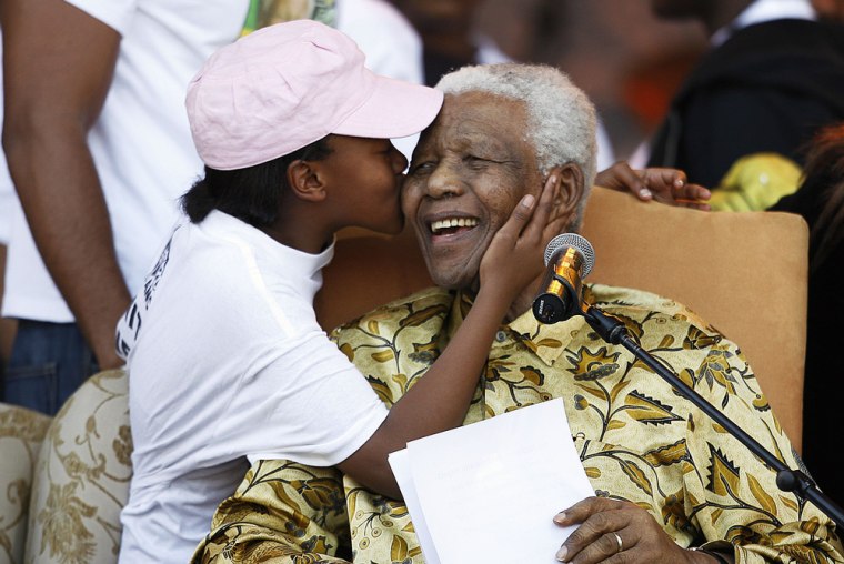 Former South African President Nelson Mandela laughs as he receives a kiss from one of his grandchildren on August 02, 2008 after giving his speech during the Mandela 90th birthday ANC celebration at Loftus stadium in Pretoria, South Africa.