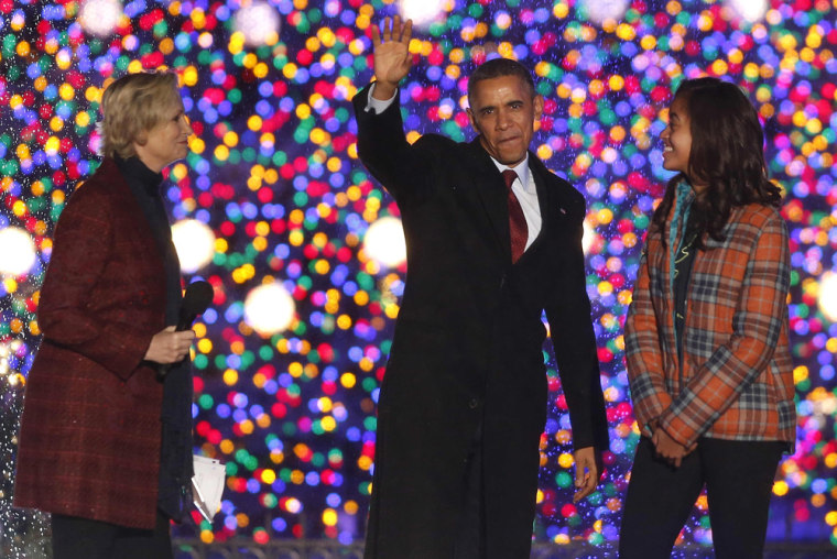 President Barack Obama waves as he stands with daughter Malia and actress Jane Lynch at the the National Christmas Tree lighting ceremony across from ...