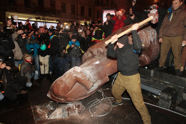 An anti-government protester beats the statue of Vladimir Lenin with a sledgehammer in Kiev, Ukraine, Sunday, Dec. 8, 2013.