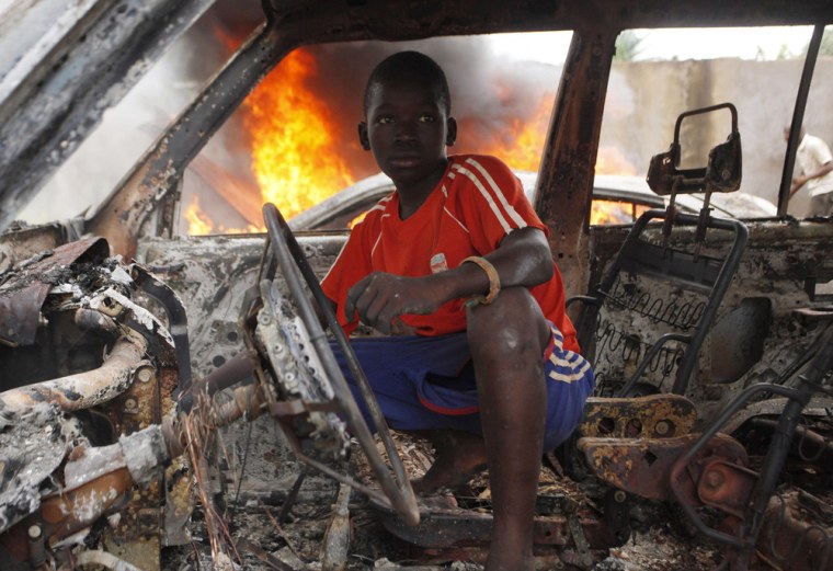 A Christian youth squats inside a burnt out car in Bangui, the capital of the Central African Republic, on Tuesday.