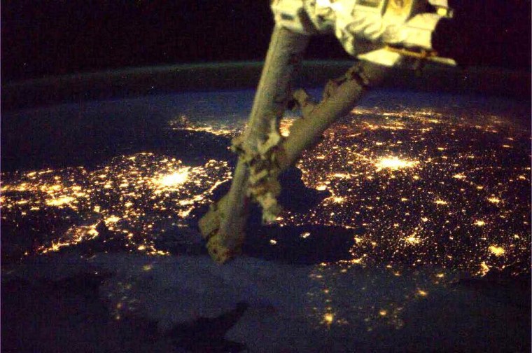 The lights of London and Paris glow in a view captured from the International Space Station. The station's robotic arm looms in the foreground. NASA astronaut Rick Mastracchio's Twitter picture has been rotated 180 degrees to produce this perspective.
