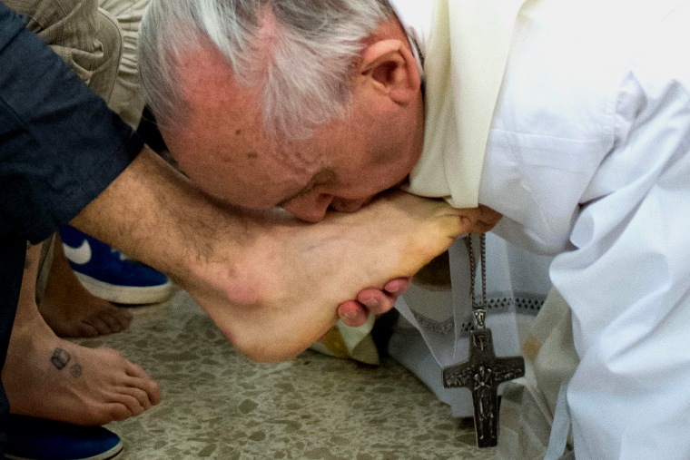 This handout picture released by the Vatican press office on March 28, 2013 shows Pope Francis (R) kissing the feet of a young offender after washing ...