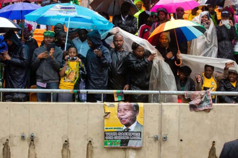 South Africans protect themselves from the rain at the memorial service for Nelson Mandela.