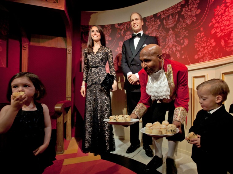 Child models eat scones as they pose with waxworks of Britain's Royal couple William and Catherine, the Duke and Duchess of Cambridge, at Madame Tussa...
