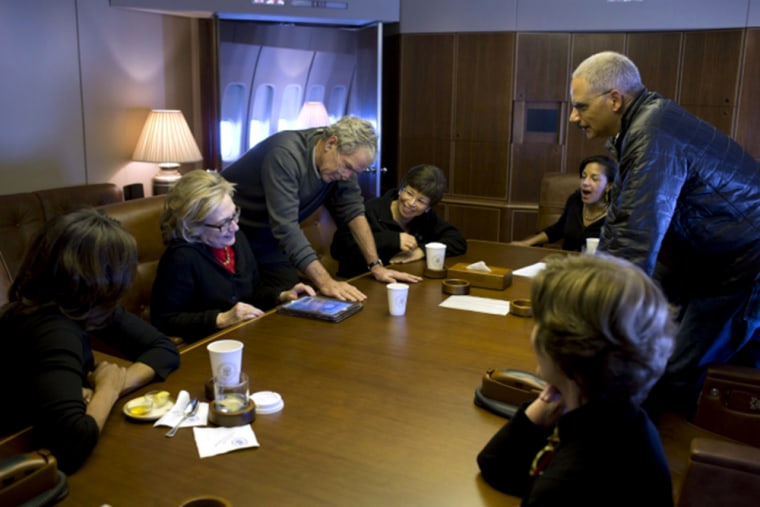 Aboard Air Force One, former President Bush shows photos of his paintings to, from left, First Lady Michelle Obama, former Secretary of State Hillary ...