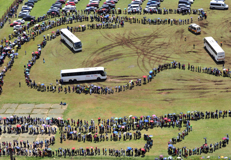 2013: Peope line up at the Pretoria show grounds Thursday to board buses that will take them to the Union Buildings where Nelson Mandela is lying in state.