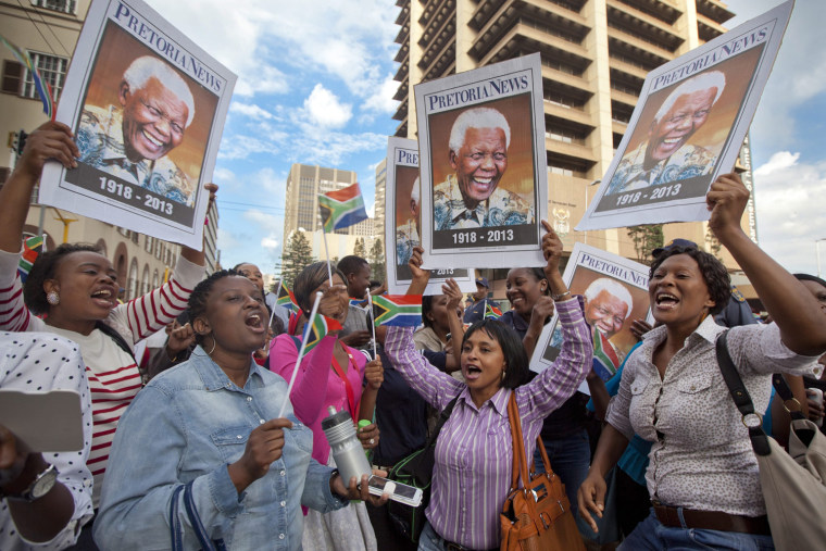 South Africans sing and dance on the street as they wait to see a hearse carrying the body of late South African President Nelson Mandela on Thursday in Pretoria.