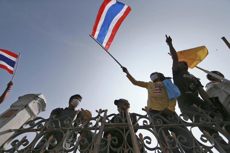 Thai anti-government protesters wave Thai national flags after removing barbed wire erected by Thai police over the fence of the Prime Minister's office known as Government House in Bangkok, Thailand Thursday, Dec. 12, 2013. Protesters waging a surreal political fight to oust Thailand's elected prime minister are trying to establish what amounts to a parallel government - one complete with "security volunteers" to replace the police, a foreign policy of their own and a central committee that has already begun issuing audacious orders. (AP Photo/Wason Wanichakorn)