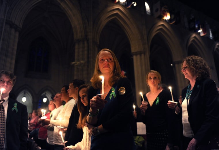 WASHINGTON - Miranda Pacchiana, center, of Newtown, Conn., holds a candle at the end of a National Vigil for Victims of Gun Violence just prior to the first anniversary marking the Sandy Hook Elementary School mass shooting at Washington National Cathedral on December 12, 2013 in Washington, DC.